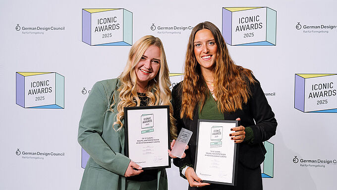 Two women are each holding a certificate in a black frame. 