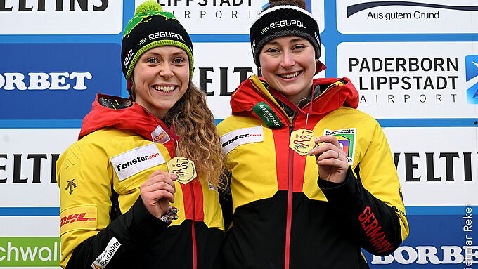 Charlotte Candrix and Lena Brunnhübner as winners in the two-man bobsleigh with gold medals and REGUPOL hats